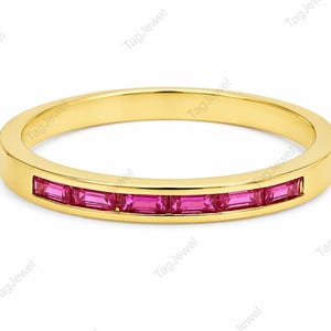 Könnte beinhalten: Ein Ring aus Gelbgold mit einer Kanalfassung, in der sechs rechteckige, im Baguetteschliff geschliffene rosa Edelsteine horizontal entlang der vorderen Hälfte des Rings angeordnet sind. Das Metall hat eine glatte, polierte Oberfläche.