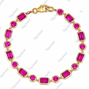 Könnte beinhalten: Ein goldenes Kettenarmband mit abwechselnd runden und smaragdgeschliffenen, leuchtend pinkfarbenen Edelsteinen in Goldfassungen. Das Armband wird mit einem goldenen Karabinerverschluss geschlossen und besteht aus Gliedern in Kreisform.