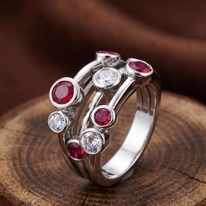 Handcrafted 925 sterling silver cluster ring featuring vibrant round lab-created ruby gemstones and sparkling white accent stones in a modern bubble-inspired bezel setting. This elegant July birthstone statement ring offers contemporary style for everyday wear, anniversaries, birthdays, engagements, Valentine's Day, Mother's Day, and thoughtful gifts for women.