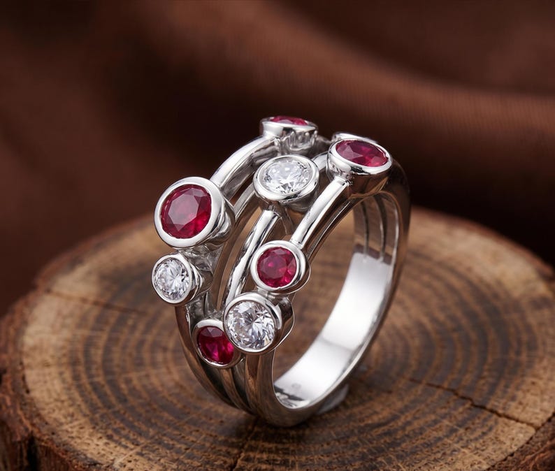 Handcrafted 925 sterling silver cluster ring featuring vibrant round lab-created ruby gemstones and sparkling white accent stones in a modern bubble-inspired bezel setting. This elegant July birthstone statement ring offers contemporary style for everyday wear, anniversaries, birthdays, engagements, Valentine's Day, Mother's Day, and thoughtful gifts for women.