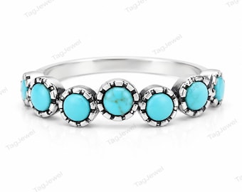 May include: A silver ring featuring a row of seven round, bright turquoise stones. Each stone is set in a scalloped, oxidized silver bezel setting that creates a textured, notched edge around the circumference of every individual gemstone.