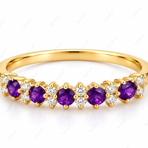 Op de afbeelding: Een gouden ring met vijf ronde paarse amethisten die worden afgewisseld met kleine clusters van heldere witte ronde diamanten. De gepolijste geelgouden zetting houdt elke steen vast in een stevige klauwzetting aan de voorzijde van de ring.