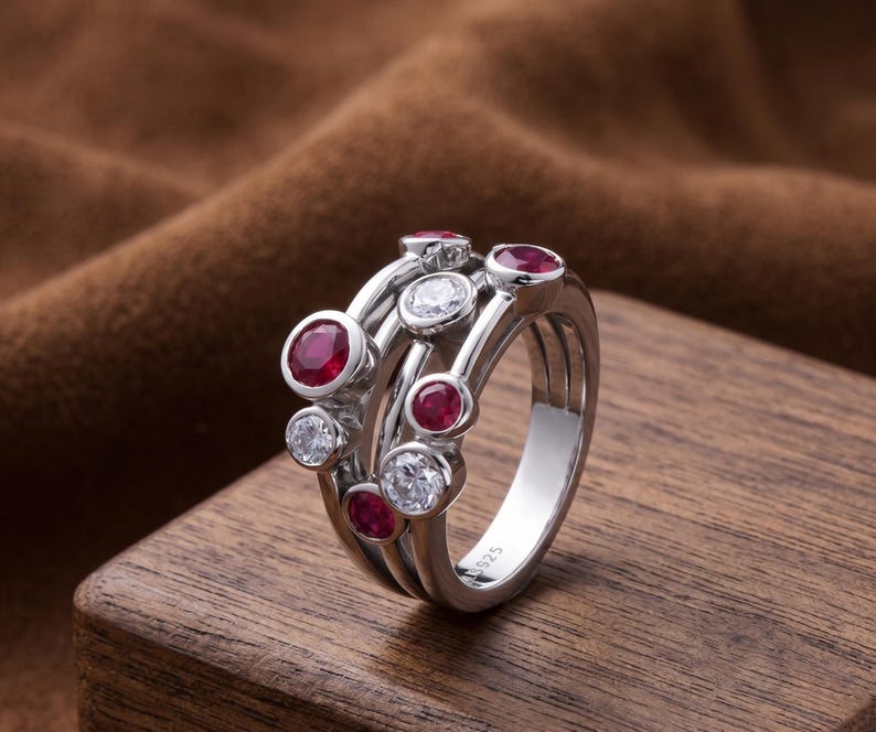 Handcrafted 925 sterling silver cluster ring featuring vibrant round lab-created ruby gemstones and sparkling white accent stones in a modern bubble-inspired bezel setting. This elegant July birthstone statement ring offers contemporary style for everyday wear, anniversaries, birthdays, engagements, Valentine's Day, Mother's Day, and thoughtful gifts for women.