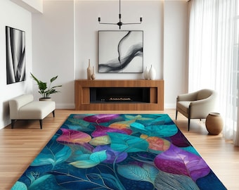May include: A large, rectangular area rug with a vibrant, abstract leaf design. The rug features a deep blue background with large, colorful leaves in shades of teal, purple, pink, and gold. The rug is placed in a modern living room setting.