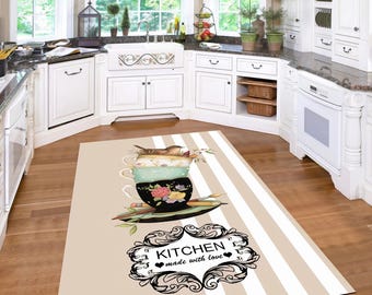 May include: A rectangular kitchen rug with a stacked teacup design, featuring a bird and floral accents. The rug has a beige background with white stripes and the text "KITCHEN made with love" in a decorative frame.