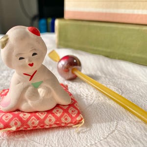 Peut inclure: Une tasse en céramique blanche avec une anse noire et le texte "But First, Coffee" en gras noir. La tasse est posée sur un fond flou, suggérant un cadre chaleureux.