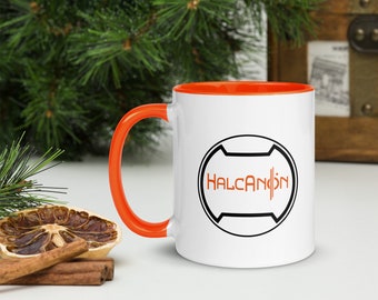 Könnte beinhalten: Weiße Keramiktasse mit orangefarbenem Rand und Henkel. Die Tasse zeigt ein schwarz-weißes Logo mit dem Text "HALCANDON" in Orange.