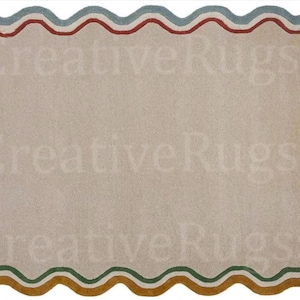 May include: A rectangular rug with a wavy border. The border has a repeating pattern of blue, red, green, and yellow-brown. The rug's central area is a neutral beige colour, and the text "Creative Rugs" is faintly visible.