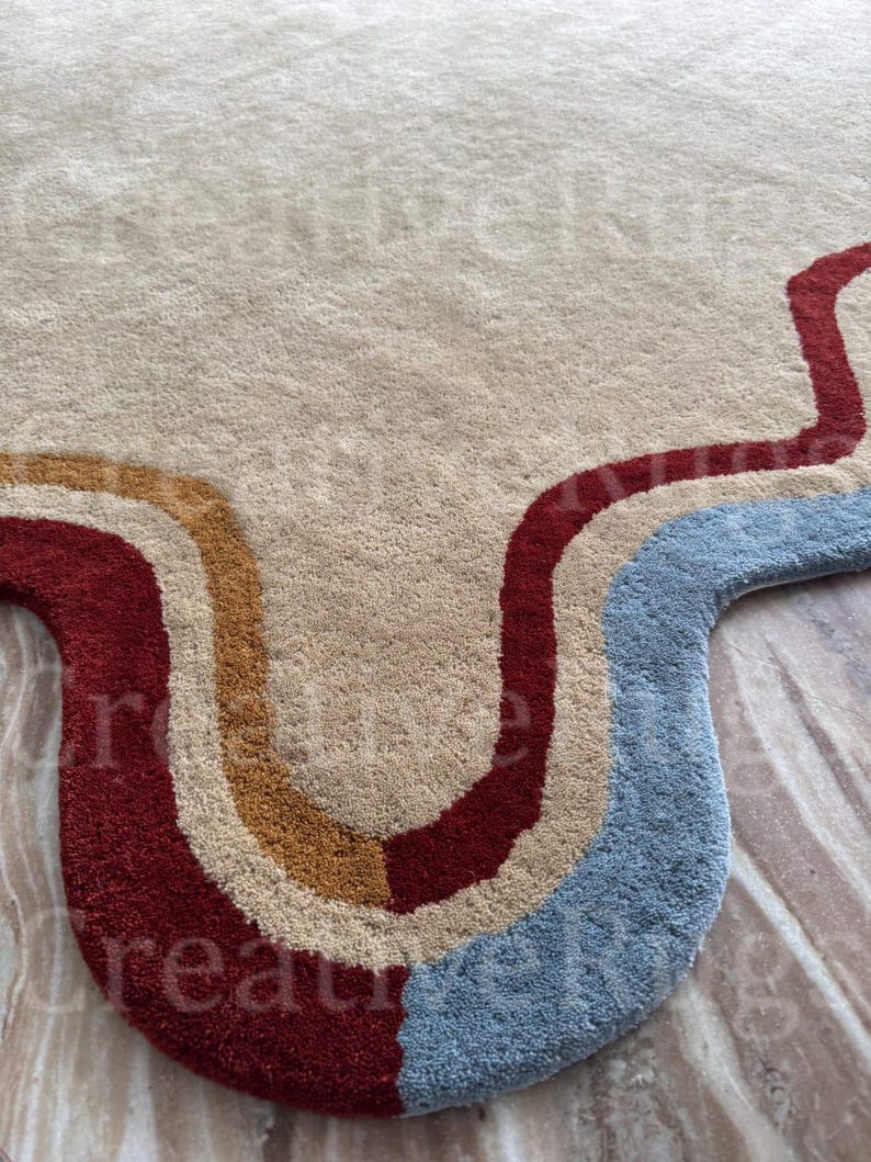 May include: A beige rug with a wavy design in red, tan, and blue. The rug has a soft, textured surface and a unique, retro-inspired pattern. The rug is suitable for a living room or bedroom.
