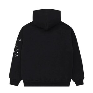 K&ouml;nnte beinhalten: Schwarzer Kapuzenpullover mit Kapuze und langen &Auml;rmeln. Der linke &Auml;rmel zeigt eine Konstellation wei&szlig;er Sterne. Der Hoodie ist aus weichem Material und f&uuml;r Freizeitkleidung geeignet.