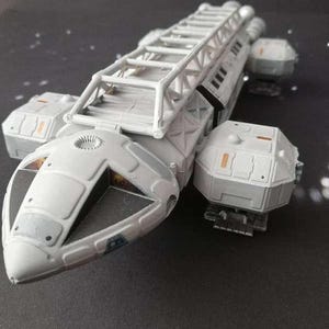 Puede incluir: Maqueta detallada de una nave espacial blanca con una estructura similar a una escalera en la parte superior. La nave espacial tiene múltiples secciones y está sobre un fondo oscuro con detalles brillantes, sugiriendo un tema espacial. Objeto de colección.