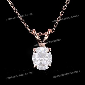 Peut inclure: Un collier pendentif en or rose avec un grand diamant rond taille brillant. Le diamant est maintenu dans un sertissage à quatre griffes, suspendu à une chaîne délicate. Le collier est présenté sur fond noir.