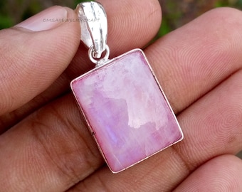 May include: A rectangular pendant with a pink and white stone set in a silver-colored metal frame. The pendant has a loop at the top for a chain. The text "OMSAIJEWELRYCRAFT" is visible on the top left.