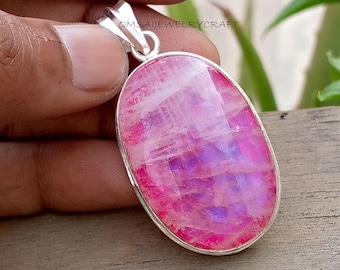 Op de afbeelding: Ovale hanger met een roze en paarse edelsteen in een zilverkleurige metalen setting. De edelsteen heeft een gepolijst, reflecterend oppervlak. De hanger hangt aan een zilveren beugel. De tekst "OMSAIJEWELRYCRAFT" is zichtbaar.