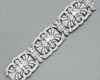 May include: A silver bracelet with an Art Deco design. The bracelet features a series of stylized floral or geometric shapes, each encrusted with numerous small, sparkling stones. The clasp is visible at the end of the bracelet.