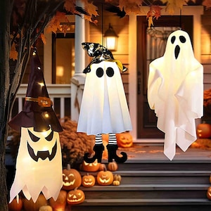 May include: Three hanging Halloween decorations: a witch with a brown hat, a ghost with a black hat, and a classic ghost. The witch has a glowing jack-o'-lantern face. The ghost with the hat has black eyes and striped legs. Pumpkins are on the steps.