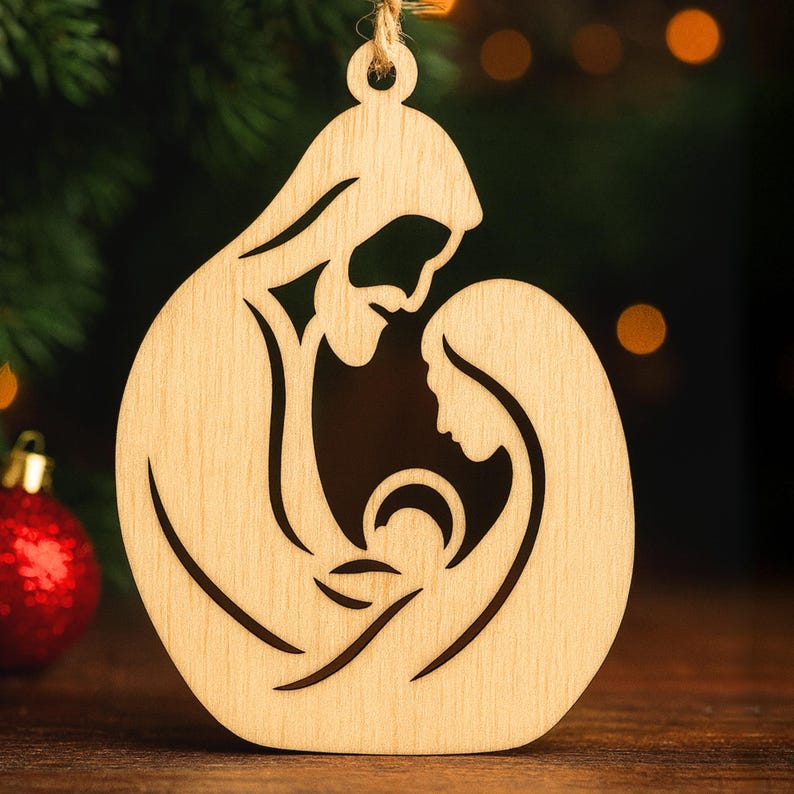 May include: Wooden Christmas ornament depicting the Holy Family: Joseph, Mary, and baby Jesus, in a cutout design. The ornament is made of light-coloured wood with a natural finish. A string is attached for hanging. The background includes a Christmas tree and bokeh lights.