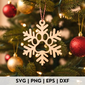 May include: A wooden snowflake Christmas ornament featuring a paw print design, suspended from a Christmas tree adorned with red and gold baubles. The text "SVG | PNG | EPS | DXF" is displayed at the bottom.