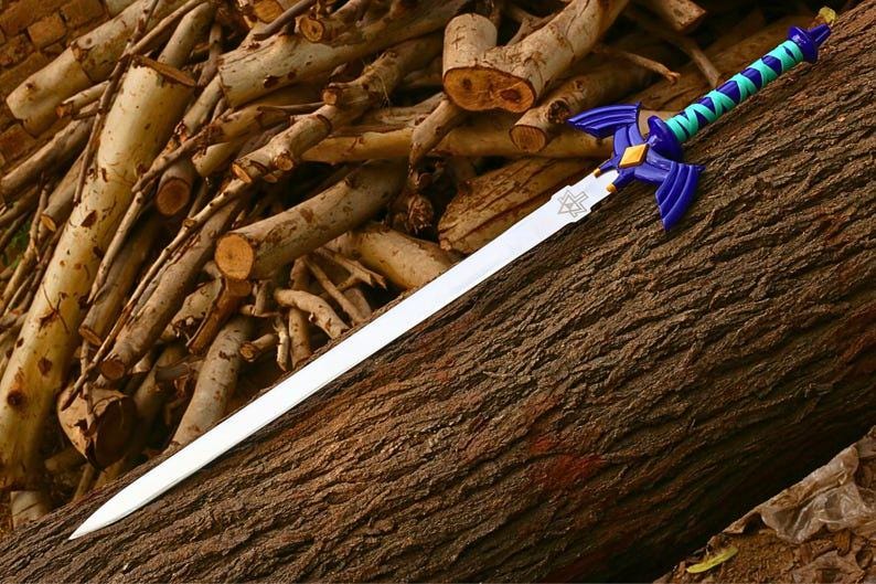 Pu&ograve; includere: Una replica di spada con lama color argento e un emblema triangolare vicino all'elsa. L'elsa &egrave; blu scuro con guardie a forma di ali, un diamante dorato centrale e un'impugnatura avvolta da fasce alternate color ottanio e blu.