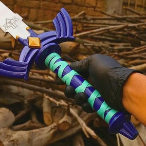 Pu&ograve; includere: Una replica di spada con lama argentata e emblema triangolare nero, una guardia blu scuro con un diamante dorato centrale e un'impugnatura avvolta da fasce alternate blu scuro e turchese chiaro, terminante con un pomolo blu scuro.