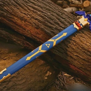 Pu&ograve; includere: Una spada blu con elsa e guardia color oro, dotata di un fodero blu abbinato decorato con motivi geometrici dorati e un simbolo triforza dorato. L'impugnatura presenta un motivo a scacchi blu chiaro e scuro con un pomolo blu.