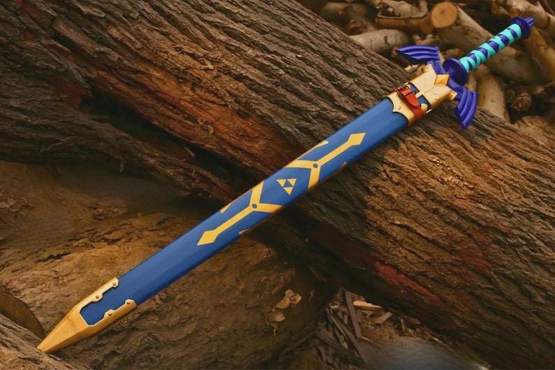 Pu&ograve; includere: Una spada blu con elsa e guardia color oro, dotata di un fodero blu abbinato decorato con motivi geometrici dorati e un simbolo triforza dorato. L'impugnatura presenta un motivo a scacchi blu chiaro e scuro con un pomolo blu.