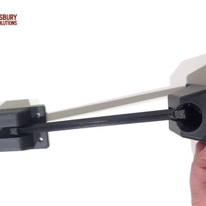 May include: Black 3D-printed wall-mounted bracket with a pivoting arm. The bracket has a rectangular base with mounting holes and a circular holder. The arm extends to a matching bracket. The image includes the text "ASBURY SOLUTIONS" and "MADE IN USA".