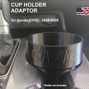 May include: Black cup holder adaptor for Honda CIVIC models from 2022-2026. The adaptor is cylindrical with the word "CIVIC" embossed on the side. The text "CUP HOLDER ADAPTOR" and "Made in the USA" are also visible.