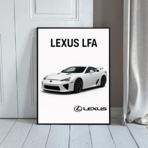 May include: A framed print featuring a white Lexus LFA sports car. The car is displayed on a white background with the text "LEXUS LFA" above and the Lexus logo below. The car has black wheels and a spoiler.