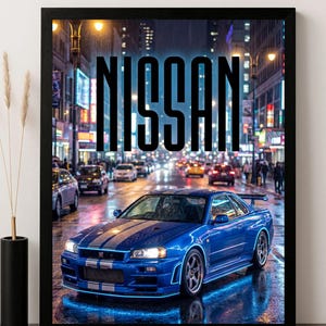 May include: A framed print featuring a blue Nissan sports car with white racing stripes, parked on a wet street at night. The word "NISSAN" is displayed in large, black letters above the car. The background shows city lights and other vehicles.
