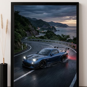 May include: A framed print featuring a blue sports car speeding along a coastal road at dusk. The car has a rear wing and black wheels. The road curves along the coastline, with mountains and the ocean in the background.