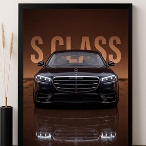 May include: A framed print featuring a black Mercedes-Benz S-Class car. The car is centered, with the text "S CLASS" in large, tan letters in the background. The car's reflection is visible below. The image is in a black frame.