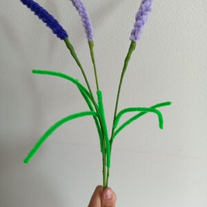 Peut inclure: Un bouquet de fleurs de lavande faites à la main. Les fleurs sont violettes et bleues, avec des tiges et des feuilles vertes. Les fleurs sont faites d'une matière duveteuse.