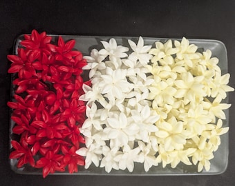 Puede incluir: Un plato rectangular de vidrio lleno de tres secciones de flores. Las secciones son rojas, blancas y amarillas. Las flores tienen múltiples pétalos y están dispuestas muy juntas.