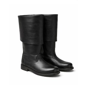 May include: A pair of black leather boots with a folded-over cuff. The boots have a rounded toe and a low, flat heel. The leather appears smooth and the boots are designed for a classic look.