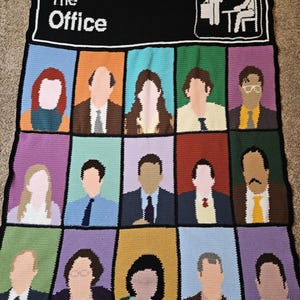 May include: A handmade crochet blanket featuring the cast of "The Office." The blanket has a black border with the show's logo and a graphic of two figures. The main body of the blanket is divided into colorful squares, each depicting a character from the show.