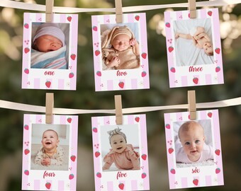 Puede incluir: Se muestran seis fotografías de bebés, cada una en un marco a rayas rosas y blancas con detalles de fresas. Las fotos están sujetas a una cinta blanca con pinzas de madera. Cada foto tiene un número del uno al seis.
