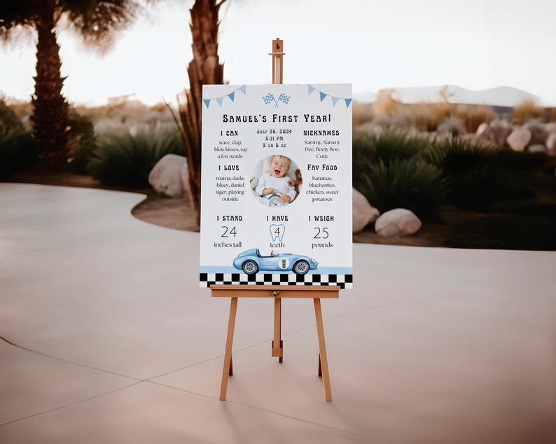 May include: A wooden easel displays a sign for a child's first birthday. The sign has a blue race car graphic and text that reads "Samuel's First Year!" with the child's photo, height of 24 inches, and weight of 25 pounds.