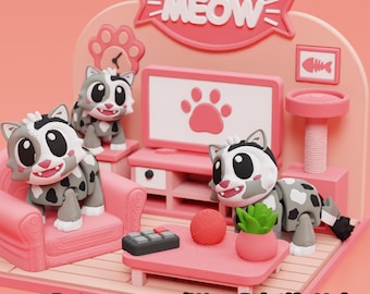 May include: A 3D printed pink cat-themed living room diorama featuring three gray and white spotted cat figurines, a pink sofa, a television with a paw print screen, a coffee table with a yarn ball, a plant, and a remote, with the text MEOW.