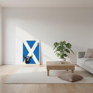Könnte beinhalten: Gerahmter Kunstdruck mit einem stilisierten schwarz-weißen Highland-Rind vor blau-weißem Hintergrund. Das Design integriert das Kreuz der schottischen Flagge. Das Wort "Hola" steht in der oberen rechten Ecke.