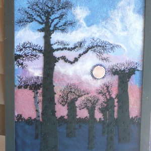 May include: A framed artwork depicting a forest scene with tall, dark trees silhouetted against a pink and blue sky. A large, white moon hangs in the sky above the trees.