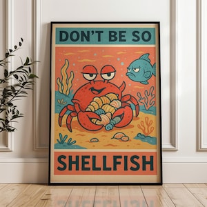 Op de afbeelding: Een ingelijste poster met een cartoonkrab die schelpen vasthoudt, met de tekst "DON'T BE SO SHELLFISH." De krab is rood, met een zelfvoldane uitdrukking, en staat tegen een zanderige achtergrond met een blauwe vis. De poster heeft een vintage, retro stijl.