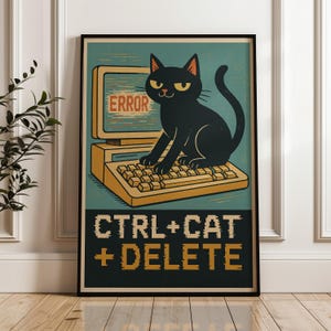 Op de afbeelding: Een ingelijste poster met een zwarte kat op een computertoetsenbord. Het scherm toont "ERROR" in het rood. Daaronder staat de tekst "CTRL+CAT+DELETE" in een pixelachtige letter. De poster heeft een retro-stijl met teal en gele kleuren.