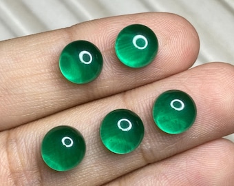 May include: Five round, cabochon-cut green gemstones with a smooth, polished surface. Each stone displays a vibrant, translucent emerald-green hue and a circular shape, reflecting light with a bright white circular highlight on the top surface.
