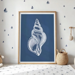 Könnte beinhalten: Ein gerahmter Druck mit einer weißen Muscheldarstellung auf marineblauem Hintergrund. Der Raum ist mit Segelboot-Wandaufklebern und Weidenkörben dekoriert, was ein maritimes Thema ergibt. Das Bild ist in einem Holzrahmen.