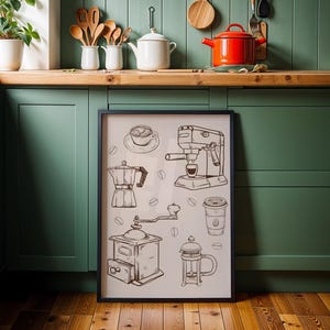 Könnte beinhalten: Ein gerahmter Schwarz-Weiß-Druck mit Illustrationen zum Thema Kaffee, darunter eine Kaffeemaschine, eine Mühle und eine Tasse. Der Druck wird in einer Küche mit grünen Schränken und einem roten Topf aufbewahrt.