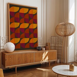 Könnte beinhalten: Ein großes, rechteckiges gerahmtes Wandbild mit einem sich wiederholenden geometrischen Muster aus orangefarbenen, gelben und dunkelroten Halbkreisen auf dunklem Grund, platziert auf einem hellen Holz-Sideboard mit vier Türen und konischen Beinen.