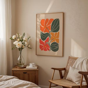 Könnte beinhalten: Gerahmter Kunstdruck mit stilisierten Blumen in Orange, Rot und Gelb mit grünen Blättern. Das Kunstwerk hängt in einem hellen Raum mit einem Holzstuhl und einer Blumenvase.