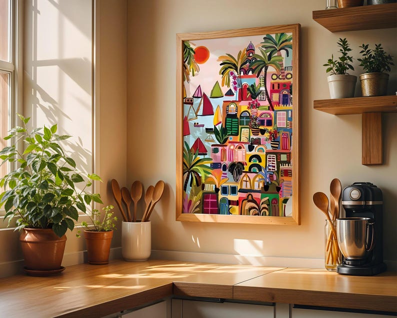May include: A colorful framed artwork depicting a coastal town scene with buildings, sailboats, and palm trees. The artwork features a vibrant palette of reds, blues, greens, and yellows. The artwork is displayed in a kitchen setting with wooden shelves and utensils.