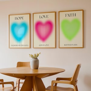 Könnte beinhalten: Drei gerahmte Wandbilder mit Herzmotiven im Farbverlauf. Das erste Bild zeigt ein blaues Herz mit dem Text HOPE und ANCHOR FOR THE SOUL. Das zweite zeigt ein pinkes Herz mit LOVE und GOD IS LOVE. Das dritte zeigt ein grünes Herz mit FAITH und ROOTED IN HIM.